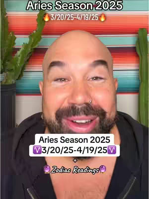 A man with a bald head, a neatly trimmed beard, and a nose ring smiles at the camera. Above him, white text on a black background reads 'Aries Season 2025', with the dates '3/20/25-4/19/25', and flame emojis on either side. In the background, behind him, colored fabrics are visible. A text box reading 'Aries Season 2025' overlaid on the bottom-center. A text overlay reads '+ Zodiac Readings'.