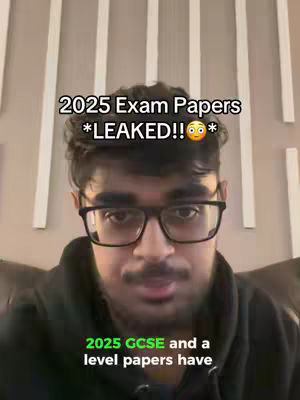 A young man with dark hair and glasses is centered in the frame, looking at the camera with a neutral expression. Above his head, text overlays read '2025 Exam Papers *LEAKED!!*' The text is white and bolded. Below him, green text states '2025 GCSE and a level papers have.' The background consists of vertical white lines against a neutral colored wall.