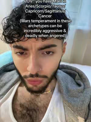 A close-up selfie of a man with dark, curly hair and a beard. Text overlays appear above his head and below his face. The background is slightly blurred.