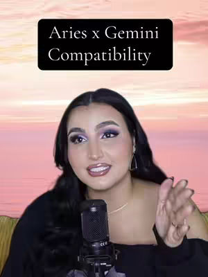 A woman with dark hair and makeup is centered in the frame against a blurred background of pink and orange hues, which gives the illusion of a setting sun. Above her, a black rectangle displays white text, while she's holding a microphone, and gesturing with her other hand.