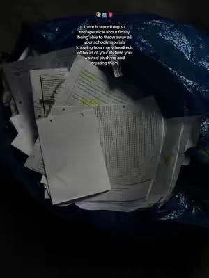 An overhead shot shows a large open blue IKEA bag filled with crumpled white papers, notes, and printed documents. The papers are haphazardly overflowing and cover the majority of the frame, suggesting a large amount of discarded school work. The text overlay, with a playful design, sits just above the center, adding text around the image, which is very dimly lit.