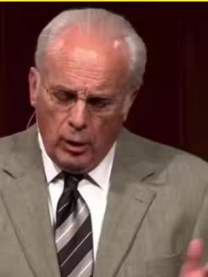 The cover image shows a close-up of an older man with gray hair, wearing glasses and a suit. He appears to be speaking, with his mouth open and a furrowed brow, and the background is dark.