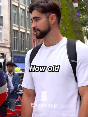 A man in a white t-shirt stands on a street corner with a building and trees in the background. The text overlay says: "How old". The image is well-lit, with the subject facing the camera, creating a direct point of engagement.