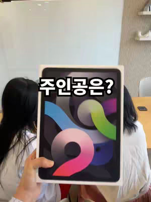 The cover image shows a person holding an iPad in its box, obscuring their face. The text overlay asks "Who is the main character?" The background includes a white wall, possibly indicating an office setting.