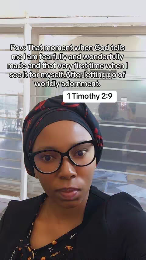 A woman with dark skin wearing black-rimmed glasses and a patterned headscarf. She is positioned in front of a window with text overlaying the image.