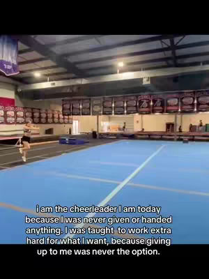 A person is performing a cheerleading move in a gym with a blue floor and awards in the background. Text overlaid on the image.