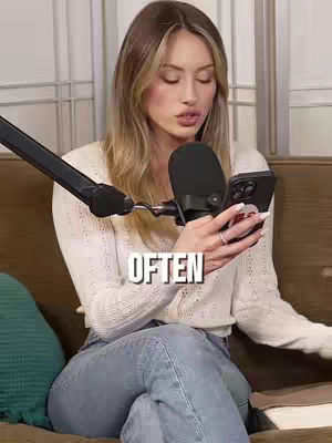A young woman with long blonde hair is seated in a chair, holding a smartphone in one hand and a microphone in the other. Text overlaid on the image reads 'OFTEN'. The background appears to be a neutral-toned room setting.