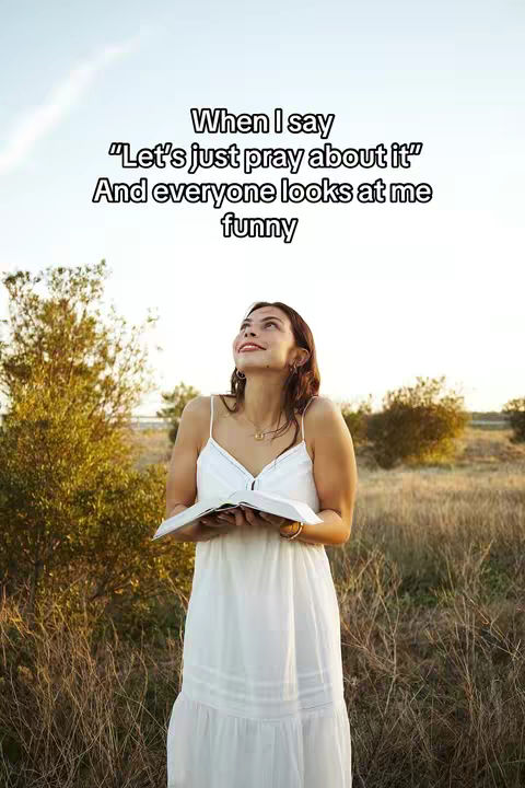 A young woman in a white dress stands outdoors in a field, looking upwards with a book in her hands. Text over the image reads, "When I say 'Let's just pray about it' And everyone looks at me funny."