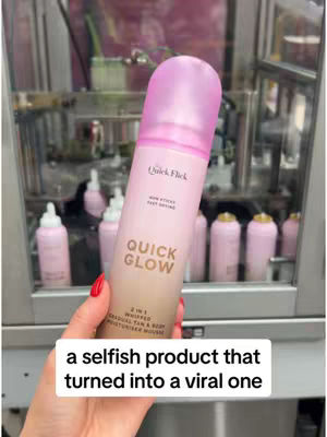 A hand holding a pink and brown bottle of Quick Glow product in front of a machine.