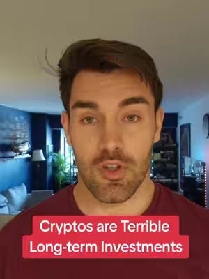 A man with short brown hair and a beard is centered in the frame. He is wearing a maroon shirt. Overlay text on the bottom reads 'Cryptos are Terrible Long-term Investments'. The background is a blurred living room setting with a blue color scheme, a lamp, and furniture.