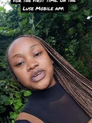 A woman with long, braided hair is the central focus against a backdrop of green foliage. She's positioned in front of vibrant leaves, framing a medium shot of her face. The image uses a natural lighting scheme, her hair falls along her shoulders, and she wears a black top. The composition is a blend of close-up and environmental detail.
