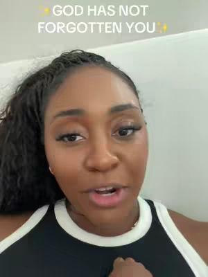 A selfie-style video shows a Black woman with long, curly dark hair pulled back into a ponytail, and wearing a black and white top. The image has text: 'GOD HAS NOT FORGOTTEN YOU' in the top.