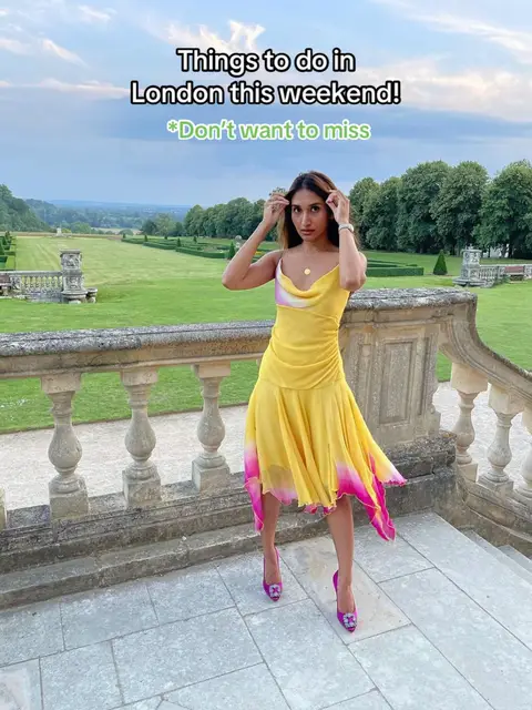 A woman in a yellow dress and pink heels stands on a stone balcony with a scenic background. The image has text overlayed.