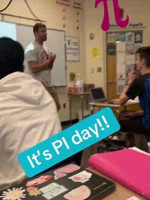 A classroom setting with a teacher standing in front of a whiteboard. A student is covering the lower left corner with their arm. A text overlay has a blue background and reads "It's Pi day!!". A large Pi symbol is visible in the top right indicating this is the focus of the subject.