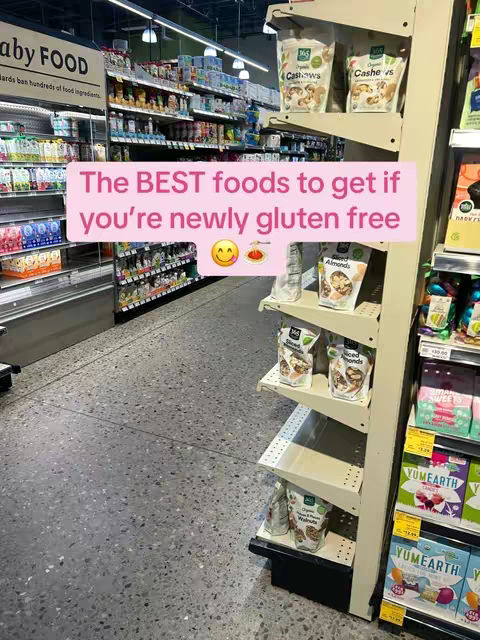 An image from a grocery store aisle. On the right, product shelves are displayed containing various packaged goods, including nuts and seeds. On the left, refrigeration units display more product. Above the products is a text overlay which says: The BEST foods to get if you're newly gluten free.