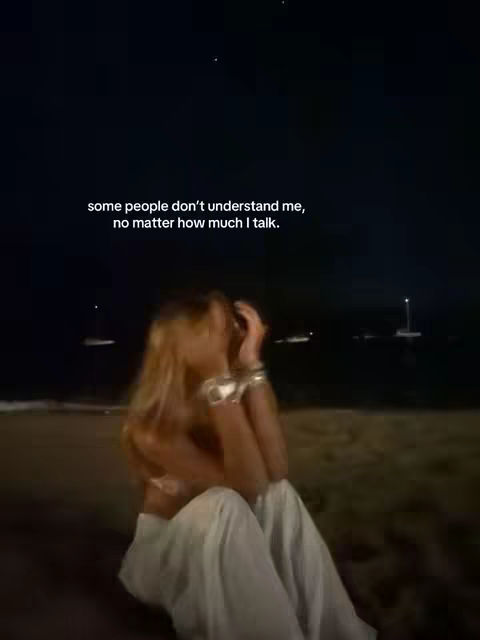 A night scene showing a person sitting on a beach with their arms wrapped around themselves. Text overlayed on the top describing the feelings of loneliness.