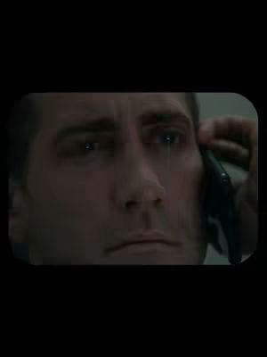 Close-up shot of a man holding a phone to his ear, with tears visibly streaming from his eyes. The image has a somber, emotional tone, accentuated by the dark background and shadow of the phone. The man's expression is one of sadness or distress.