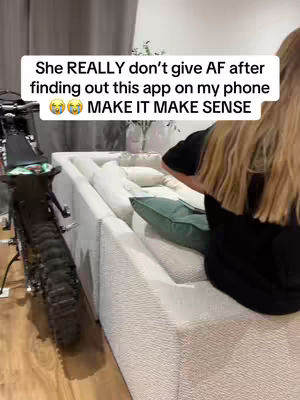 The cover image features a living room scene. A woman with long blonde hair is partially visible on the right side of the frame. A white couch, some throw pillows, and a black motorcycle on the left provide additional context.