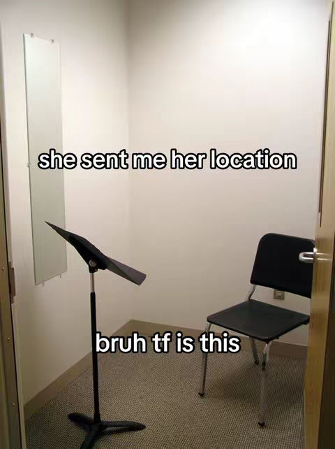 The image shows a dimly lit practice room with a music stand in the middle ground and a black chair to the right. Above the music stand, the background is a wall-mounted, long mirror. The room has beige walls and a carpeted floor. Text overlays the image: 'she sent me her location' and 'bruh tf is this'.