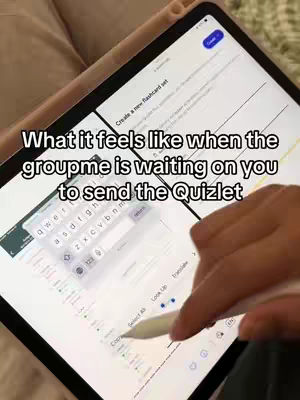 A person's hand is operating a tablet, with a white stylus touching the screen. The screen displays a white interface with text, a keyboard, and a copy/paste menu, against a backdrop of a light-colored surface.
