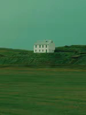 An image of a white house on a grassy hill with a green sky.