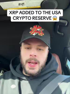 A man wearing a black cap and hoodie is seated in a car, looking at the camera. A text overlay reads, 'XRP ADDED TO THE USA CRYPTO RESERVE' with surprised emojis. The background suggests an enclosed vehicle setting.