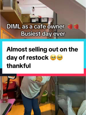 The cover image showcases a behind-the-scenes look at a cafe. In the upper portion, a person's arm and back are partially visible, possibly stocking shelves, with boxes and shelves in the background. Below, a teal box of text announces the cafe's almost sold-out situation along with the cashier's gratitude. In the bottom portion, a person is captured from the waist down; they appear to be tending to something, partially hunched over in an interior setting.