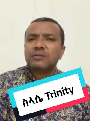 A man with dark hair and a patterned shirt is centered in a medium shot. A rectangular text overlay in the lower-middle part of the image reads "ስላሴ Trinity". The background is a plain off-white color.