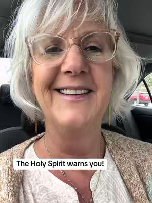 The cover image features a close-up of a woman inside a car. She wears a white blouse, a brown sweater and eyeglasses. Text overlayed at the bottom reads, "The Holy Spirit warns you!"