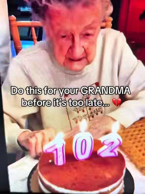 An elderly woman is seated, seen from the chest up, in front of a birthday cake decorated with lit candles that display the number 102. Text on the cover image encourages viewers to act for their "GRANDMA."