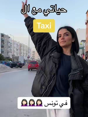 A woman stands on a city street, hailing a taxi with her arm raised. She wears a dark jacket and looks toward the right. Text overlays include Arabic script and the word \"Taxi\" in a yellow box. The background shows buildings and cars.