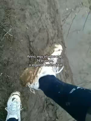 The image shows an extreme close-up from a first-person perspective of two muddy white sneakers as the ground is shown from the inside