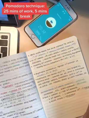 A top-down shot shows a notebook with handwritten notes open on a desk. A phone is positioned above, displaying a timer with a blue background and white circle, and the text 'Pomodoro technique: 25 mins of work, 5 mins break' overlayed at the top.