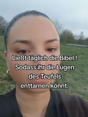 A medium shot shows a fair-skinned woman with dark hair pulled back and a neutral expression. Text overlays her face. She appears to be outdoors, with greenery and overcast sky in the background.