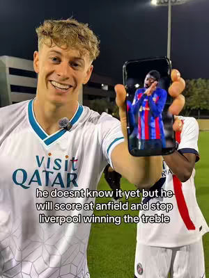 A young man in a white soccer jersey smiles widely, holding a smartphone that displays an image of a soccer player in a red and blue uniform. The background is a green field with a stadium and a dark sky. Text overlays at the bottom of the image.