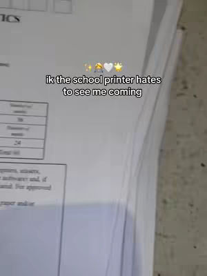 The image shows a stack of printed papers, likely for exams. The text overlay reads "ik the school printer hates to see me coming" with some emojis. The papers are white with some text and tables visible.