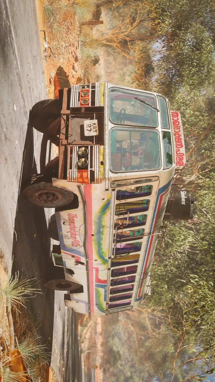 A detailed, photorealistic 3D render of a colorful, vintage bus on a road. The bus is white with blue, pink, and green stripes and text in Malayalam is visible. The bus sits on a roadway with trees and vegetation surrounding it, creating an outdoor setting.