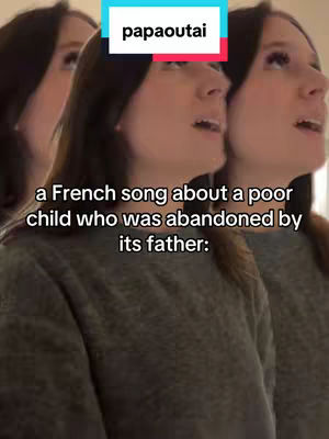 The cover image is a selfie featuring a woman, triplicated to create a stylized repeating effect. The woman is facing slightly to the side and looking upwards as if singing. Above her head, a rectangular box displays the word "papaoutai". Below the primary figure, overlayed text provides context, and is likely the hook for the video. The background appears uncluttered with soft lighting, and the color palette is muted with shades of gray and a slight peach lighting.