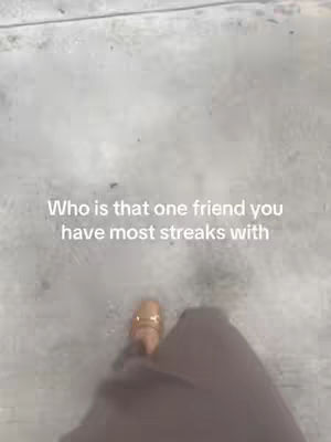 An overhead shot shows a person's feet in brown pants and sandals walking on a light gray surface that seems to be concrete. Overlayed on the image, the text reads, "Who is that one friend you have most streaks with."