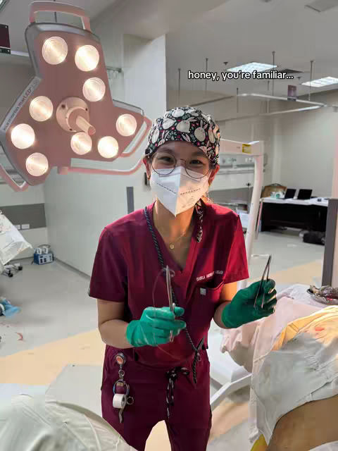 A woman in medical attire, wearing a surgical cap and mask, holds surgical tools in an operating room setting. The image has soft lighting with a text overlay.