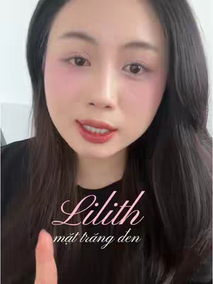 A close-up of a woman with long dark hair looking at the camera. She has pink blush on her cheeks and red lipstick. Text overlays the image.