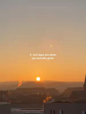 The image shows a sunrise or sunset over a cityscape. The sky is a gradient of orange and yellow.