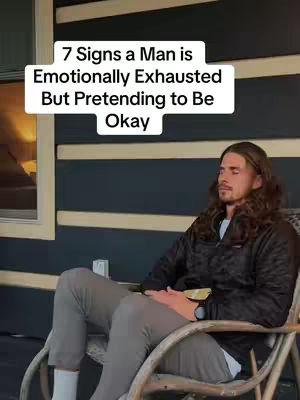 A man with long hair sits relaxed on a rocking chair on a porch, eyes closed suggesting meditation or contemplation.