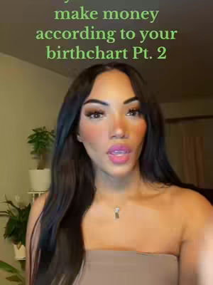 A woman with long dark hair and makeup is centered in the frame, with text overlayed in the upper-middle section of the frame. The background is a neutral color with some plants in pots visible.