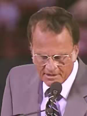 The cover image features a medium shot of an older man speaking into a microphone. He is wearing glasses, a suit, and a tie. The background is blurred, but appears to be an indoor event setting.
