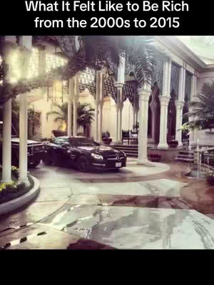 The image showcases a black sports car parked in front of a grand, elaborate mansion or estate. The building has a series of white pillars and arches, with palm trees adding a tropical feel. The scene is bathed in sunlight, possibly suggesting a bright, luxurious environment. The text overlay at the top reads, \"What It Felt Like to Be Rich from the 2000s to 2015.\"