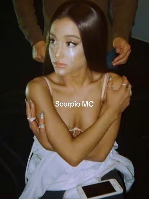 The image features a woman with dark hair, wearing light-colored clothing. She appears to be looking at the camera with a composed expression, with a tear rolling down her cheek. The overlay text "Scorpio MC" is displayed on the upper left of her.