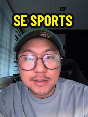 A man with glasses and a cap is centered in the frame. Above his head is a yellow banner with bold text. Behind him is a dark background.