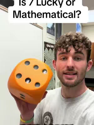 The cover image shows a young man holding a large orange die in his hands. The image is brightly lit with a classroom or office setting in the background. Text overlayed on the image reads: "Is 7 Lucky or Mathematical?"