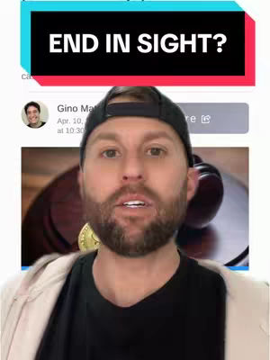 A man in a black cap and black shirt with a gold coin visible in a video frame. A text overlay at the top says "END IN SIGHT?"